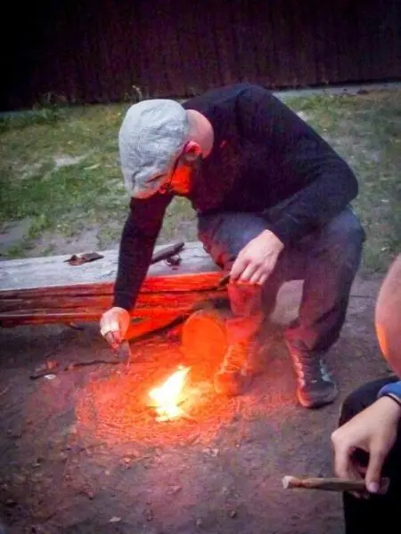 Person zündet Feuer mit Stöcken im Freien