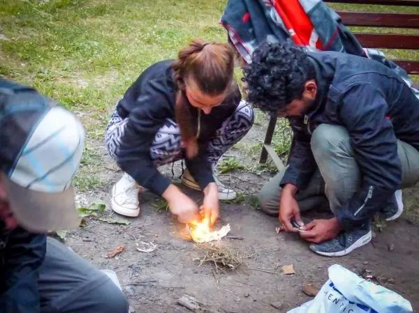 Person zündet Feuerstelle mit Zunder an beim Survival Training