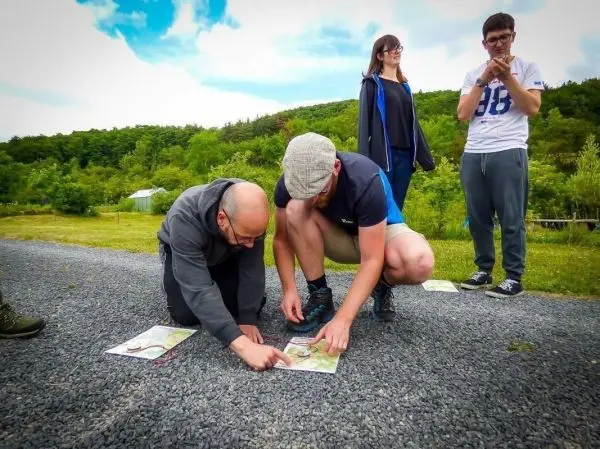 Zwei Personen studieren Karten auf dem Boden, während zwei weitere zuschauen