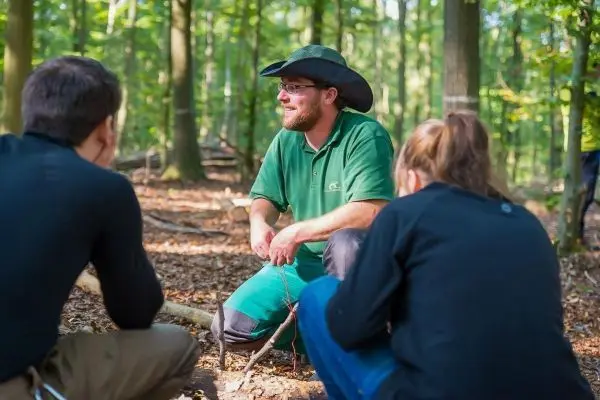 Ein Mann erklärt Techniken zur Holzverarbeitung in einem Wald