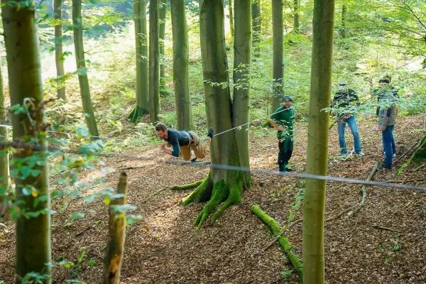 Ein Mann nutzt eine selbstgebaute Seilbrücke zwischen Bäumen