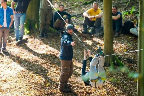 Ein Teilnehmer nutzt eine Seilbrücke, während ein Trainer Anweisungen gibt