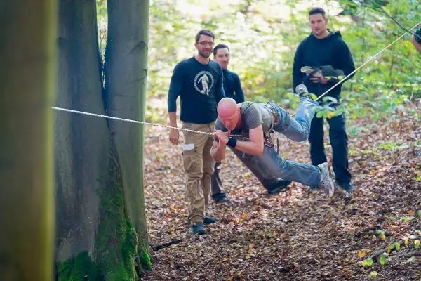 Ein Teilnehmer schwingt an einer Seilbrücke zwischen zwei Bäumen