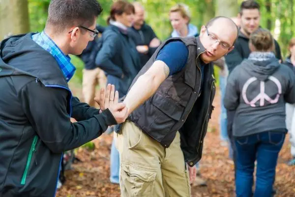 Ein Teilnehmer übt eine Erste-Hilfe-Technik am Arm eines anderen im Wald