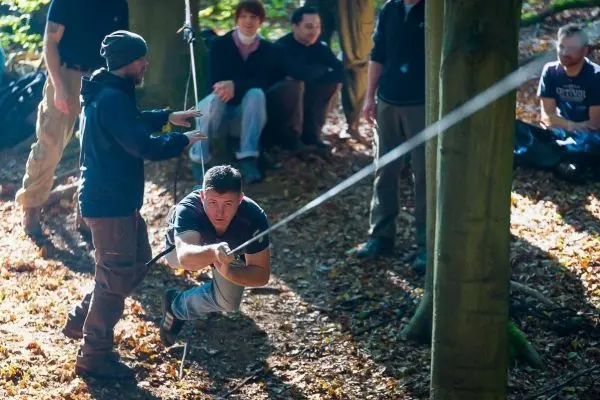 Ein Teilnehmer zieht sich an einem Seil zwischen Bäumen entlang