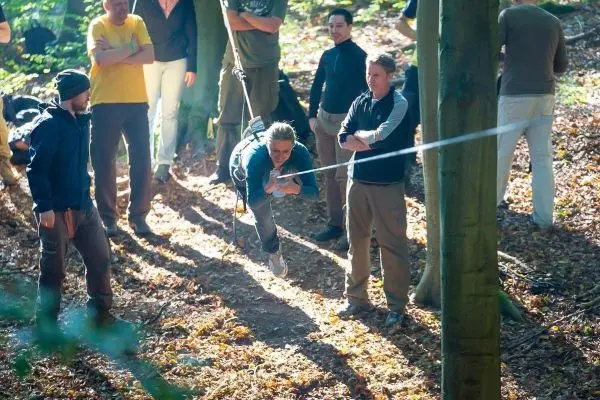 Eine Person schwingt an einer Seilbrücke zwischen Bäumen hindurch