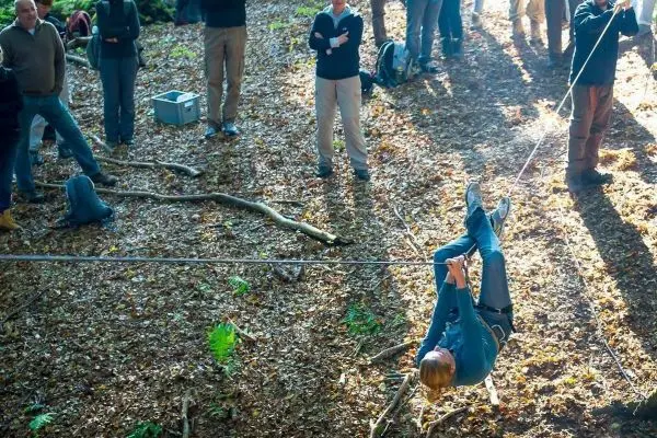 Eine Person überquert eine selbstgebaute Seilbrücke zwischen Bäumen