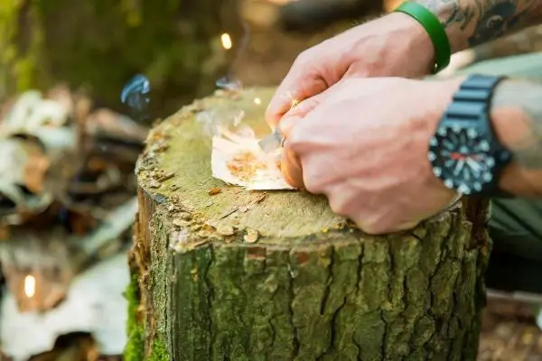 Feuerstahl erzeugt Funken auf Zunder auf einem Baumstumpf