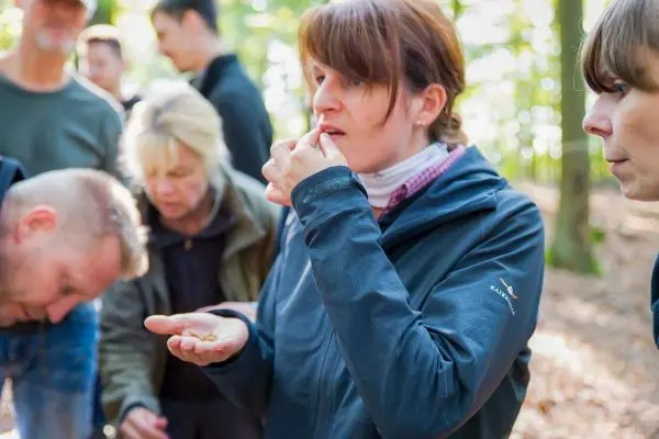 Frau hält etwas in der Hand und probiert es im Wald