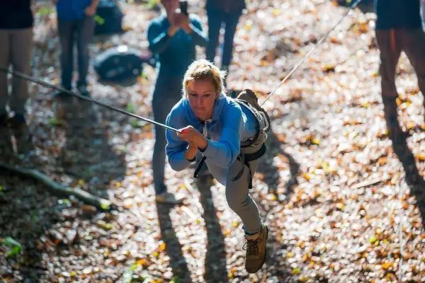 Frau schwingt an Seil über den Waldboden