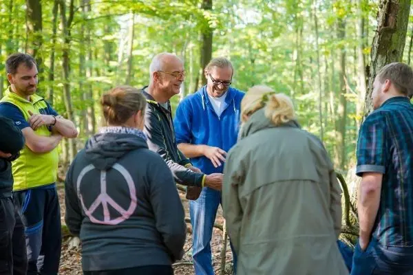 Gruppe diskutiert im Wald um einen Tisch mit Ausrüstung