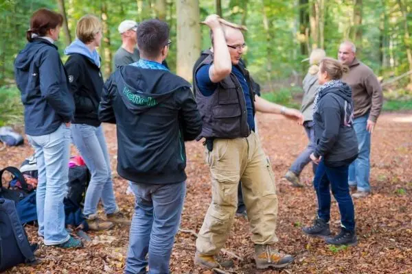 Gruppe übt Techniken zur Selbstverteidigung im Wald auf Laubboden