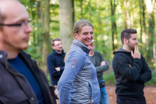 Gruppe von Personen steht im Wald und beobachtet eine Aktivität