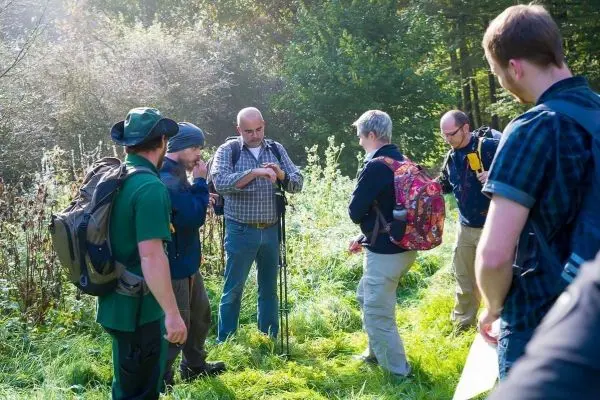 Gruppe von Wanderern diskutiert Ausrüstung im grünen Gelände