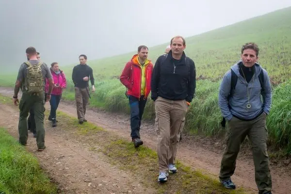 Gruppe wandert auf einem schmalen Weg durch neblige Landschaft
