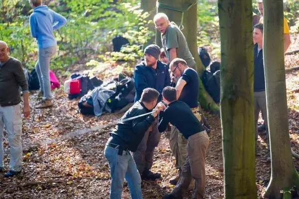 Gruppendynamik beim Training in einem Waldgebiet mit Rucksäcken im Hintergrund