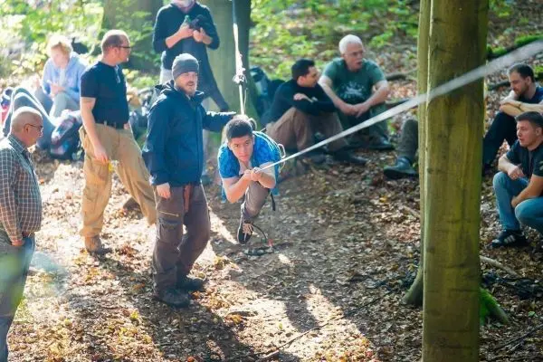 Junge nutzt Seil für eine selbstgebaute Seilbrücke zwischen Bäumen