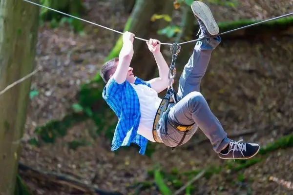 Junge schwingt an einer Seilbrücke durch den Wald