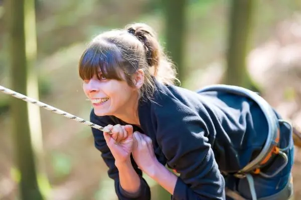 Kletternde Person zieht sich an einem Seil in einem Wald hoch