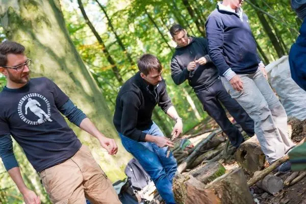 Männer bearbeiten Holzstücke im Wald mit Werkzeugen