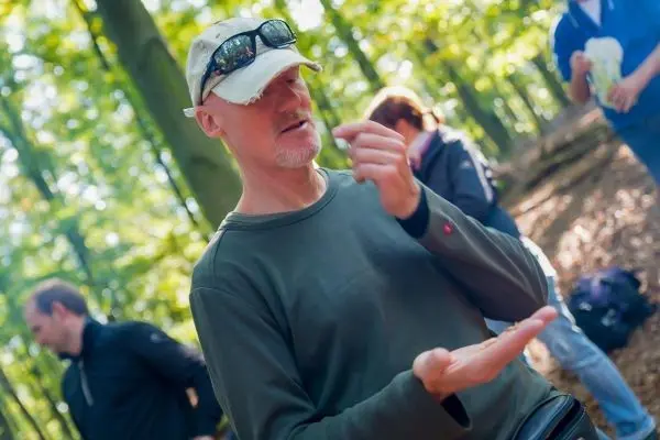 Mann erklärt eine Technik im Wald, während andere Teilnehmer zuhören