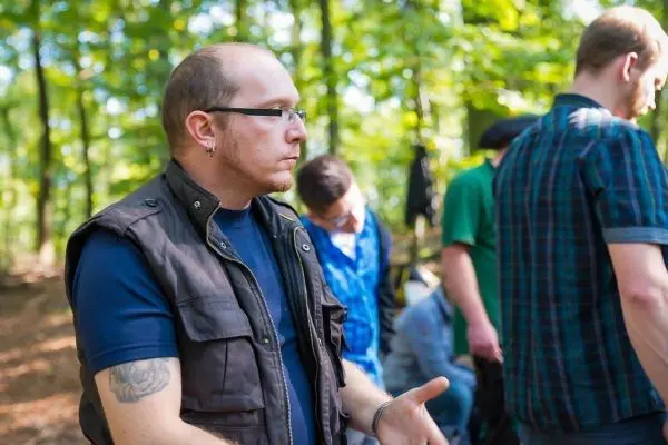 Mann mit Brille und Weste gestikuliert im Wald