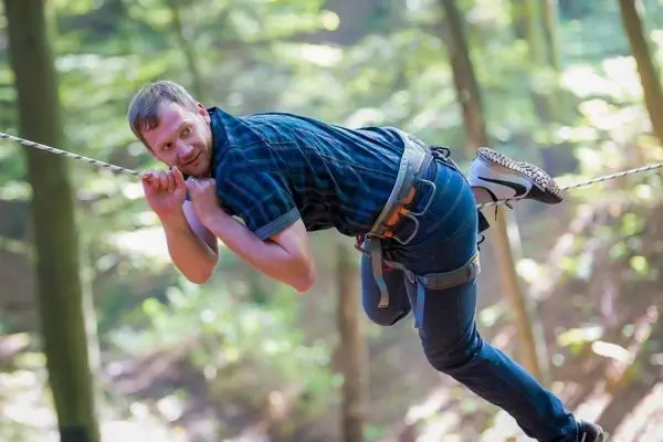 Mann nutzt Seil zur Fortbewegung zwischen Bäumen im Wald