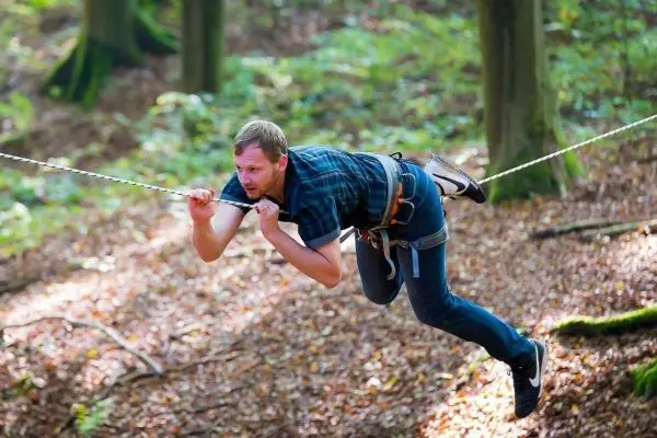 Mann schwingt an einer Seilbrücke durch den Wald