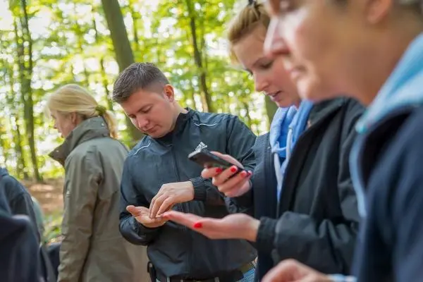 Mann überprüft Smartphone, während Frauen in der Nähe ihre Hände betrachten