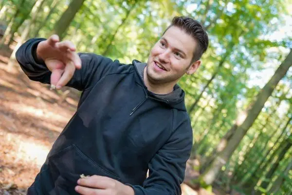 Mann zeigt gestikulierend etwas in einem Waldgebiet