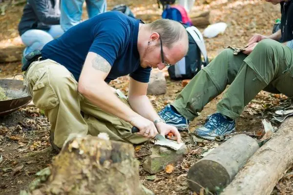Messer bearbeitet Holzstück auf dem Boden im Wald