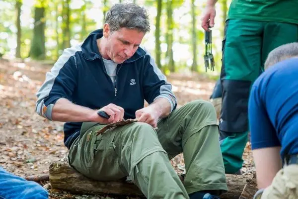 Messer bearbeitet Holzstück auf einem Baumstamm im Wald