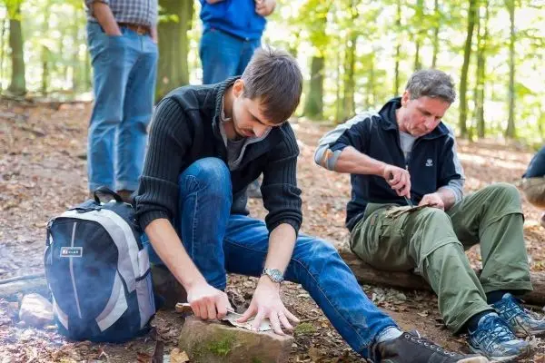Messer schneidet Holzstücke auf einem Stein im Wald