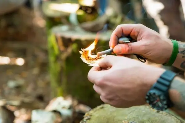 Person entzündet Zunder mit Feuerstahl beim Survival Training