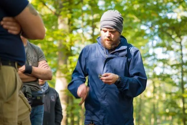 Person erklärt etwas einer Gruppe im Wald