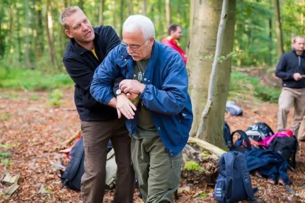 Person hilft anderer Person beim Anlegen einer Uhr im Wald