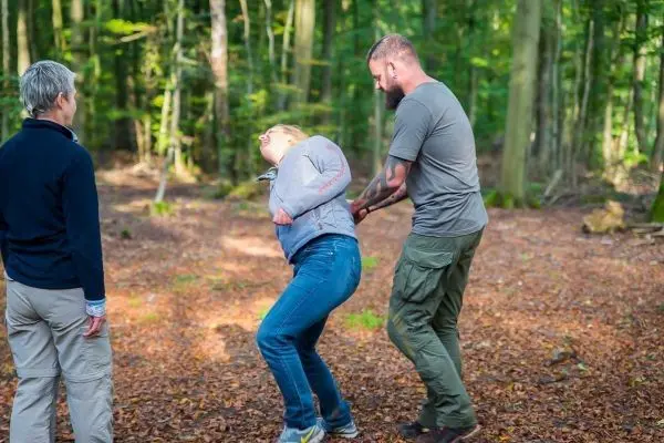 Person hilft anderer Person beim Aufstehen im Wald