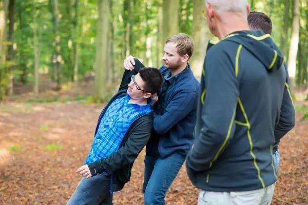 Person hilft anderer Person beim Üben einer Technik im Wald
