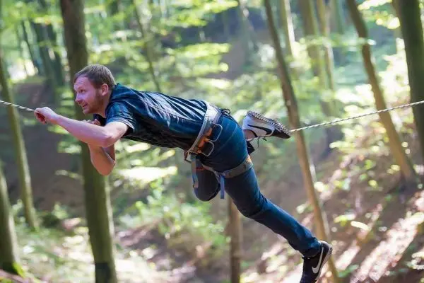 Person schwingt an einem Seil durch den Wald