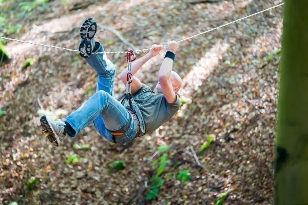 Person schwingt an einer Seilbrücke durch den Wald