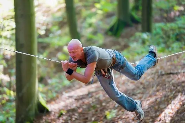 Person schwingt an einer Seilbrücke durch den Wald