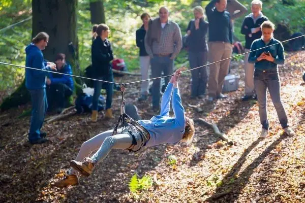 Person schwingt an einer Seilbrücke durch den Wald