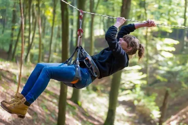 Person schwingt an einer Seilbrücke durch den Wald