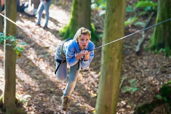 Person schwingt an einer Seilbrücke zwischen Bäumen