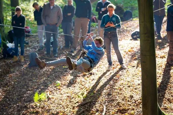 Person schwingt an einer Seilüberquerung im Wald