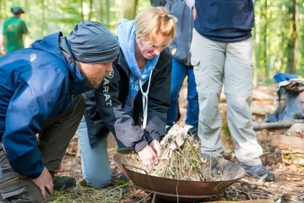 Personen bauen ein Feuer mit trockenem Material im Wald