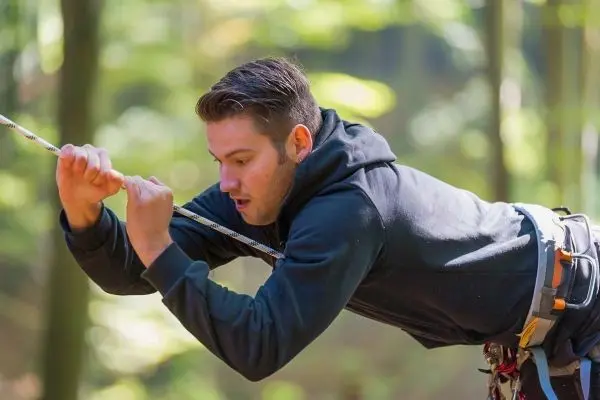 Seil wird mit beiden Händen festgehalten während des Abseilens im Wald