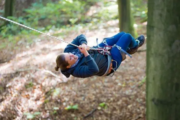Seilbrücke verbindet zwei Bäume, während eine Person schwingt