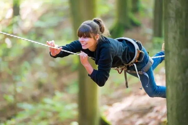 Seilbrücke wird zwischen zwei Bäumen überquert