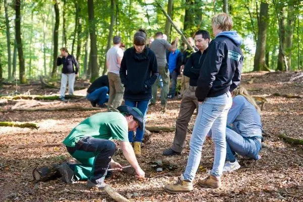 Teilnehmer üben im Wald das Entzünden von Feuer mit Zunder und Feuerstahl